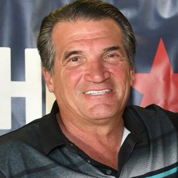 Smiling middle-aged man in a black and gray shirt with a background featuring a star.