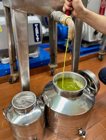 Green liquid flowing into a metal container from a pipe in an industrial setting.