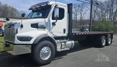 White flatbed truck parked on road.