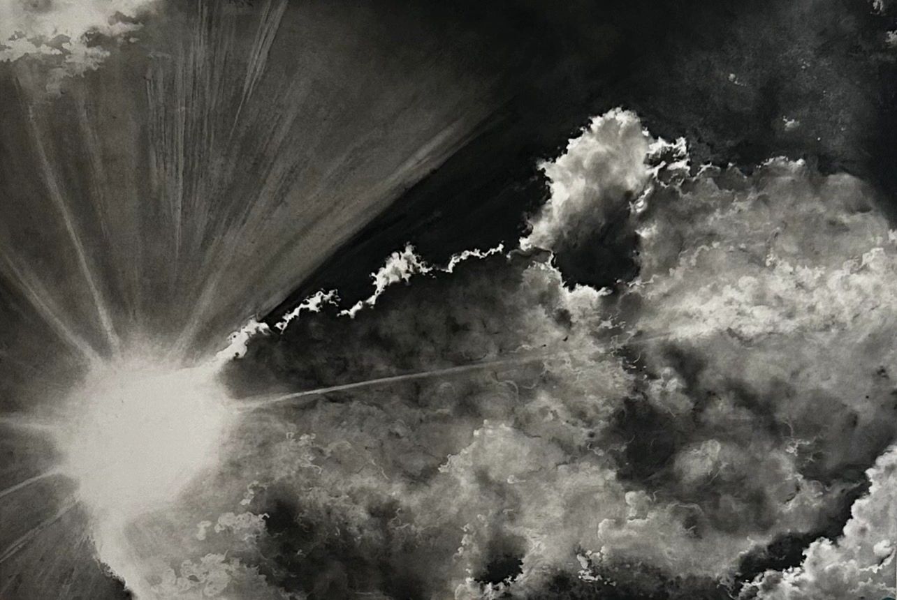 Dramatic black and white clouds with bright sunlight rays breaking through.