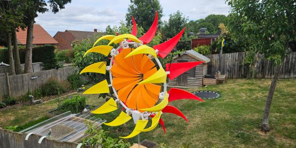 Colorful wind spinner with red, yellow, and orange blades in a garden.