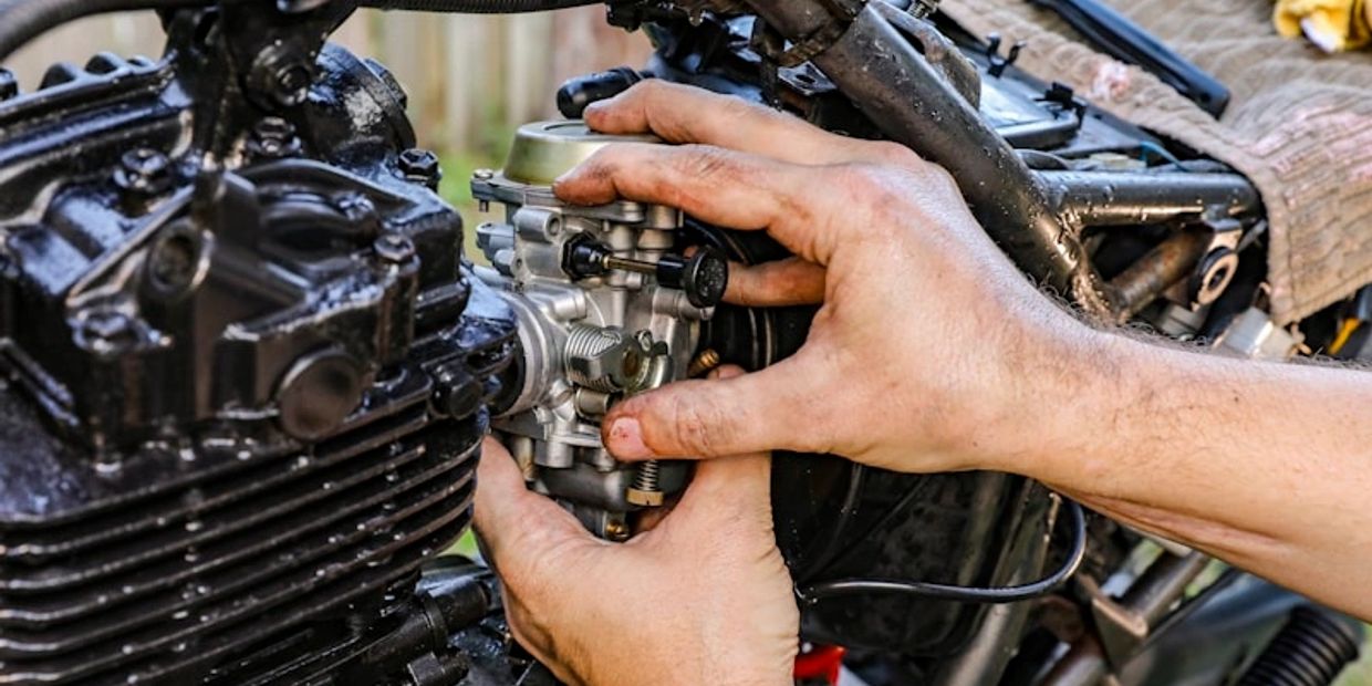 Hands fixing a motorcycle engine component.