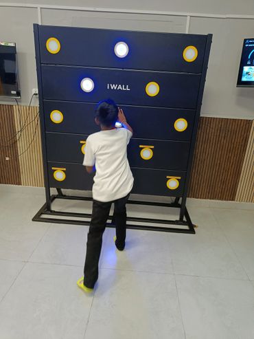A boy playing a fitness games called iWall inside The Play Kingdom, a kids play area in coimbatore.