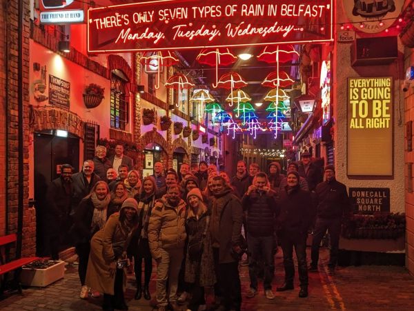Group photo under colorful umbrella lights in Belfast street.
