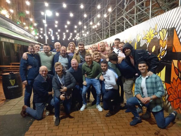 Group of friends posing together at night under string lights.