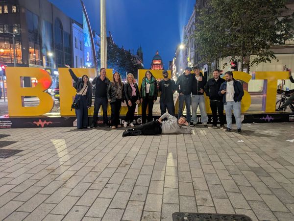 Group of people posing at night in front of large colorful letters.
