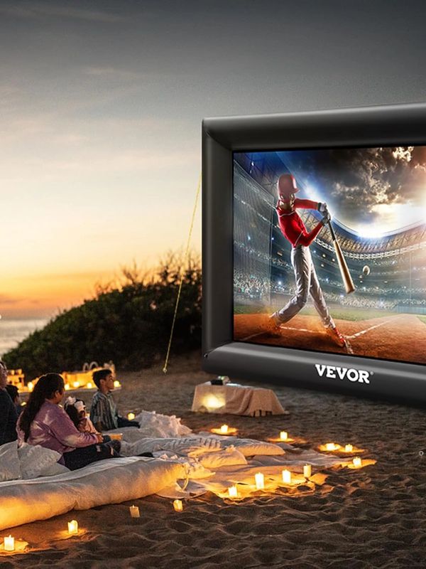 Outdoor movie night on the beach with people watching a baseball game.