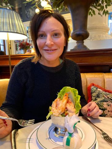 Woman smiling at a restaurant table with a shrimp cocktail.