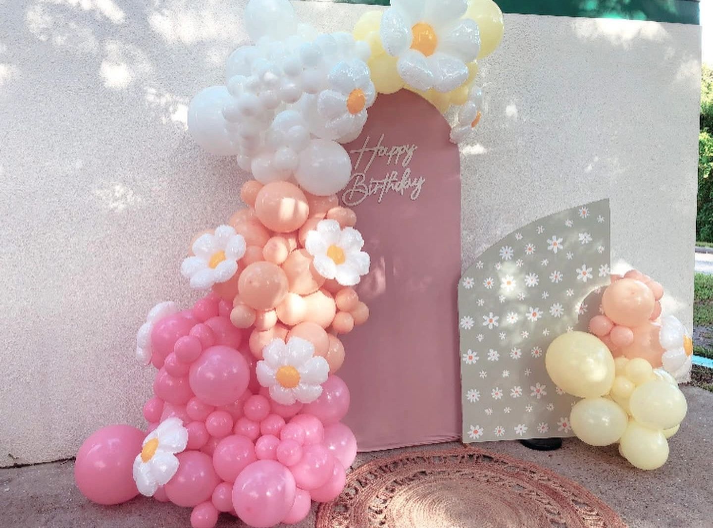 Colorful balloon arch with floral decorations for a birthday celebration.