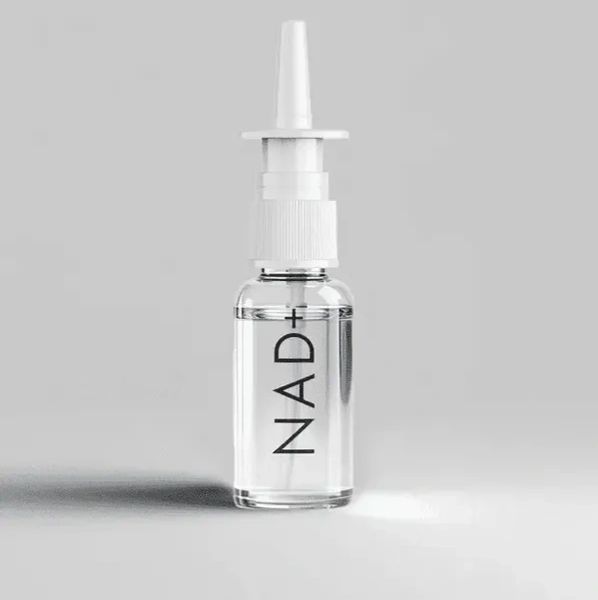 Clear nasal spray bottle labeled NAD+ on a gray background.