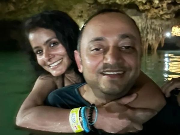 Two people enjoying a swim in a cave pool, smiling happily.