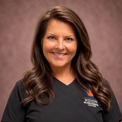 Smiling woman with long brown hair in a black shirt.