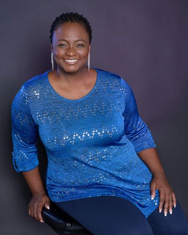 Canangela is sitting and smiling to show her charisma as an actress and voice talent.