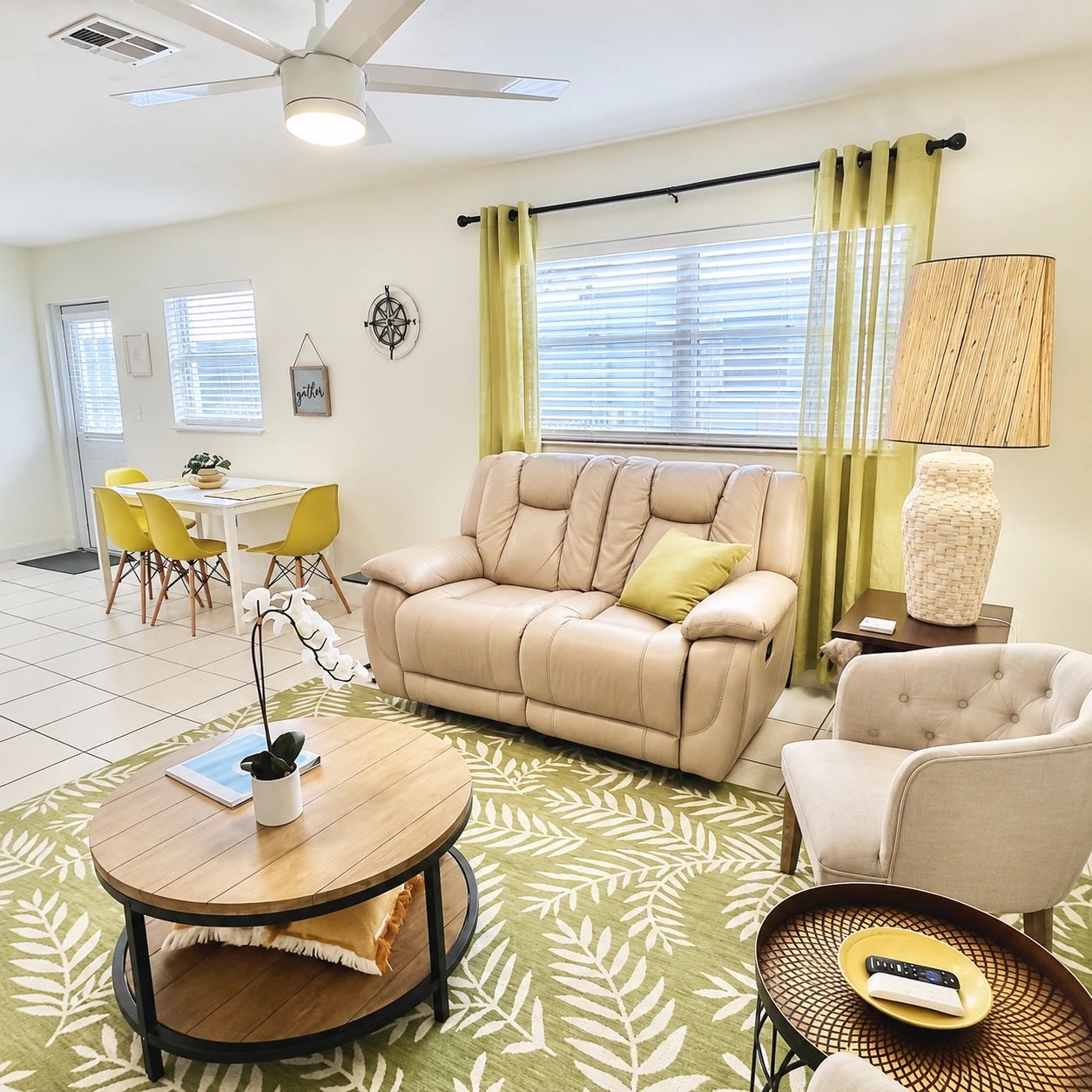 Bright living room with beige sofa, green curtains, and yellow dining chairs.