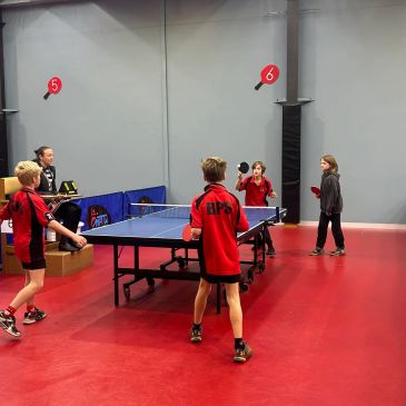 Kids playing table tennis indoors.