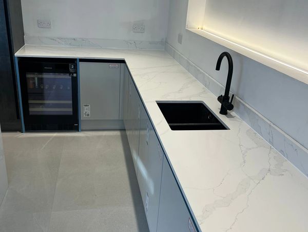 Modern kitchen with marble countertop and black sink and faucet.