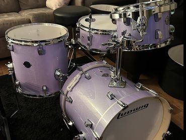 A purple Ludwig drum set with multiple drums arranged in a living room.
