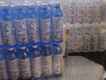 Packs of alkaline water bottles labeled 'Time 2 Alkaline' with pH 9.5-10.5.