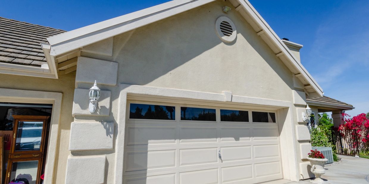 Front of a beige house with a closed garage door.