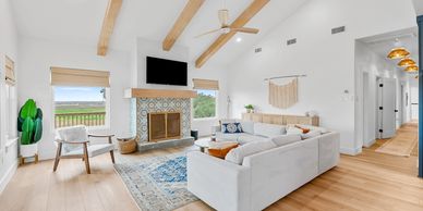 Bright modern living room with vaulted ceiling, fireplace, and large windows.