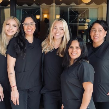 Group of five smiling women in black uniforms.