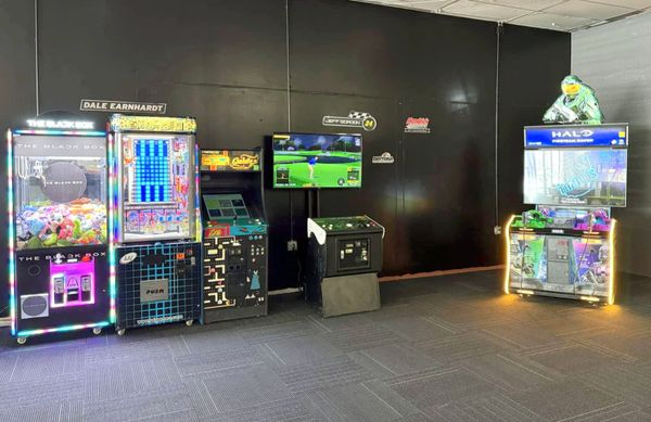 A group of friends enjoying classic arcade games, surrounded by colorful lights and excitement.