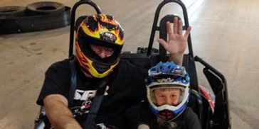 A father and son gear up to race go karts on a professional track, capturing the excitement karting!