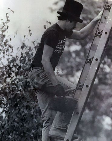 Chimney sweep with a chimney brush climbing a ladder to access the roof of a home