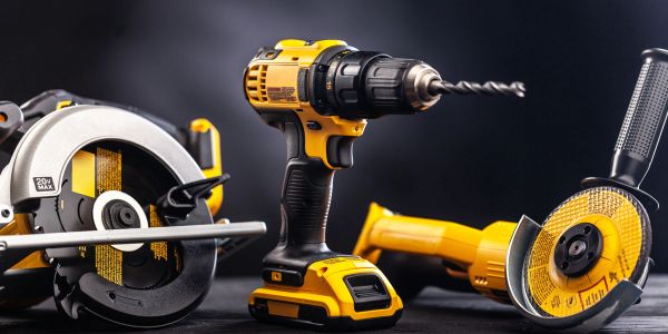 Yellow power tools including a drill, circular saw, and angle grinder on black background.