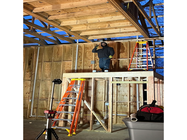 Man standing on a wooden platform inside a building under construction.