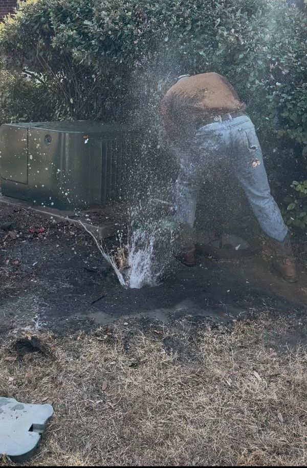 Person struggling with a burst water pipe spraying water everywhere.