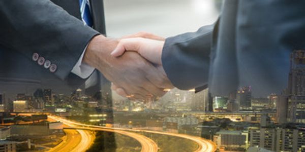 Two businessmen shaking hands with a cityscape overlay.