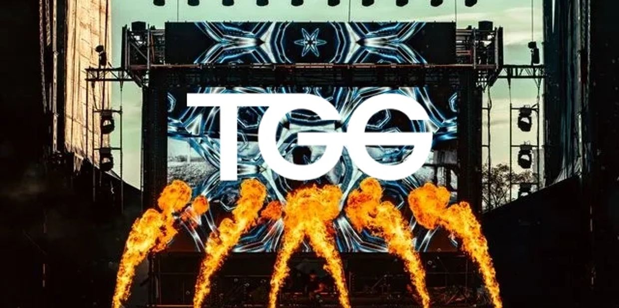 Concert stage with flames and TGG logo on screen.