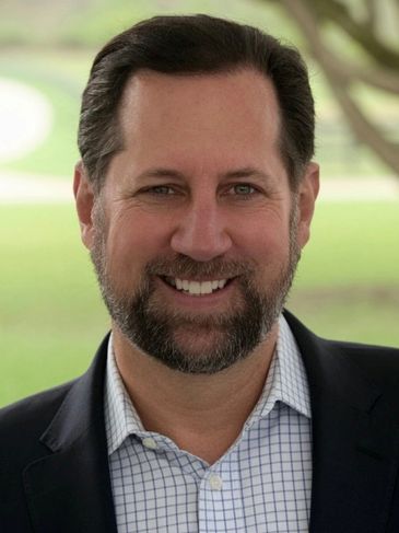 Smiling man in a business suit outdoors.
