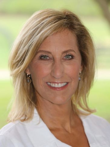 Smiling blonde woman with light background.