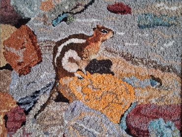 Small squirrel on rocky ground.