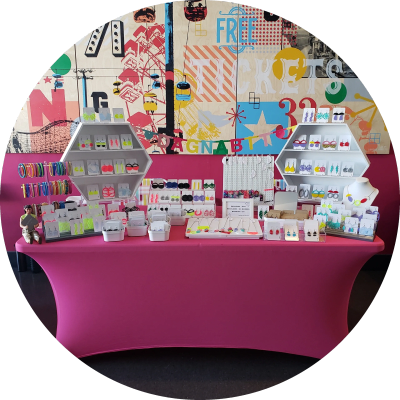 Colorful handmade jewelry display on pink tablecloth.