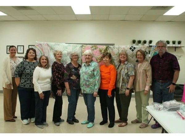 Group of ten smiling older adults posing indoors.
