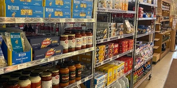 Grocery store aisle with shelves stocked with pasta, sauces, and packaged goods.
