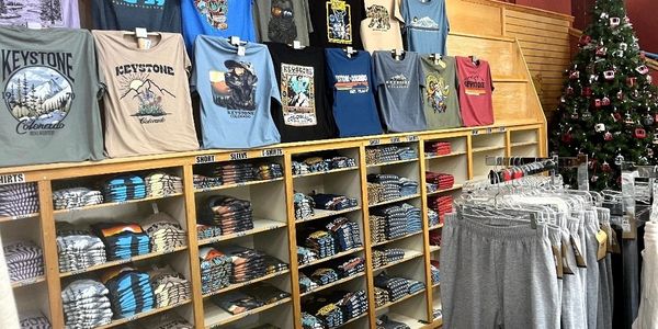 A retail display of Keystone-themed t-shirts and sweatpants near a decorated Christmas tree.