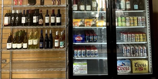 Shelves and fridge stocked with various wines, beers, and beverages.