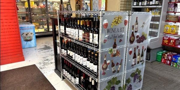 Wine bottles displayed on a metal rack with promotional banners in a store.
