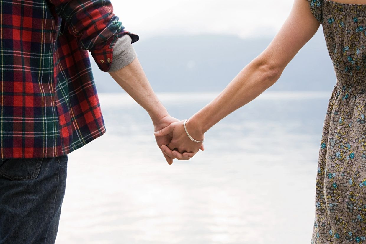Couple holding hands near a body of water.