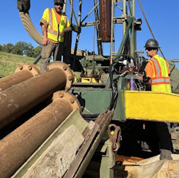 Two construction workers operating heavy machinery outdoors.