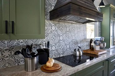 Green cabinets with wood hood and pattern tile backsplash