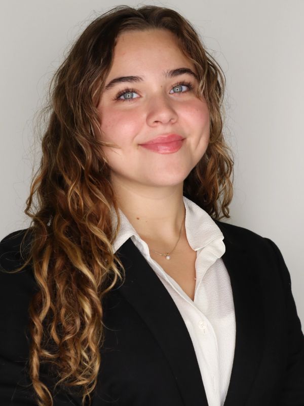 Portrait of a young woman with curly hair in formal attire.