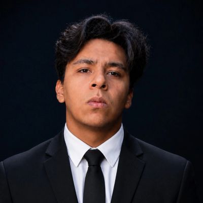 Hombre joven con traje negro y corbata.