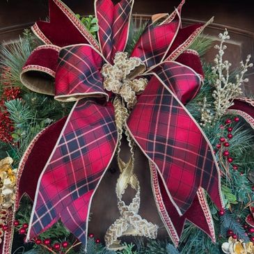 Large red plaid bow on a festive holiday wreath.