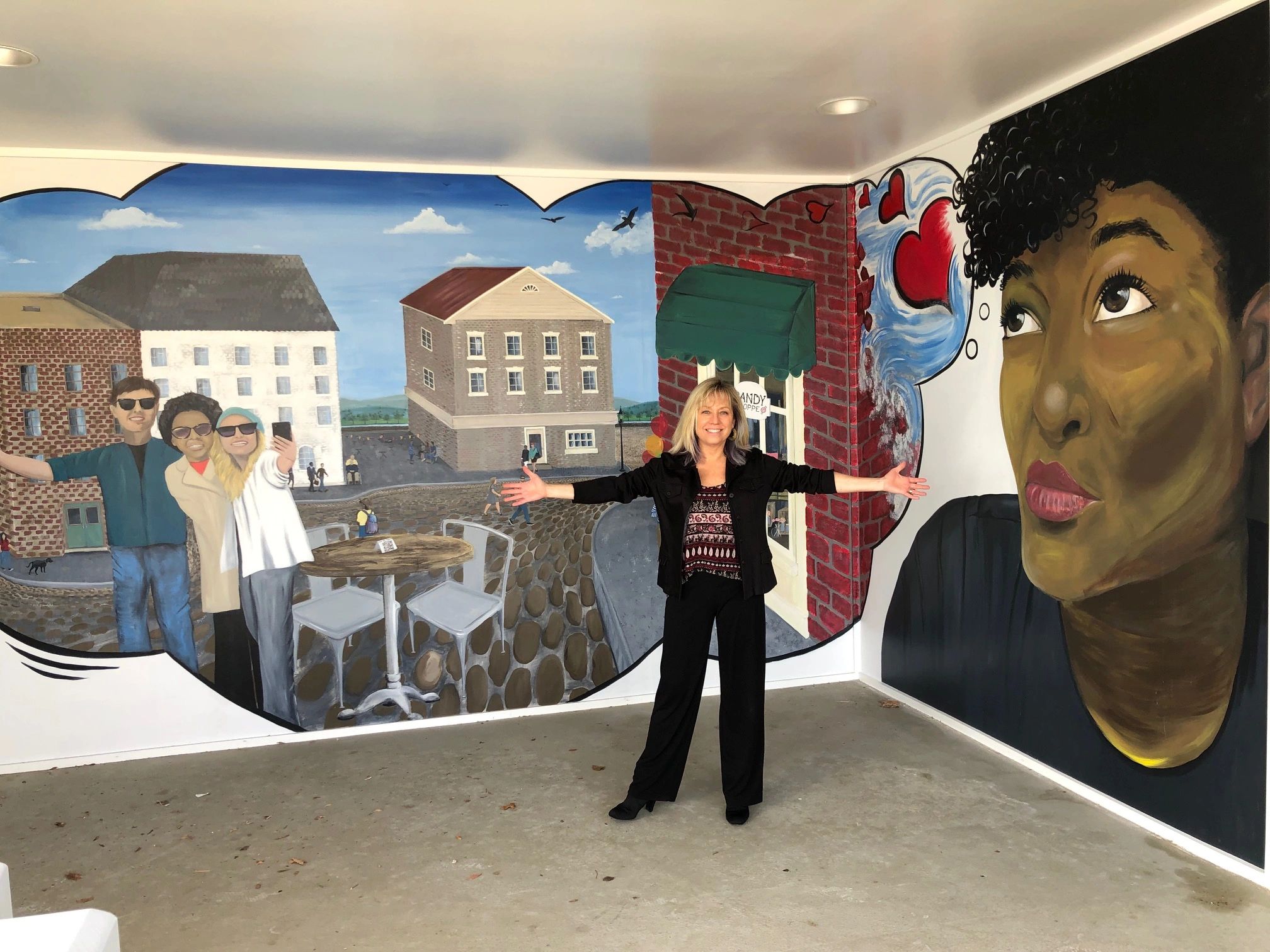 Kelly standing in front of a public mural she painted in Virginia, USA.
