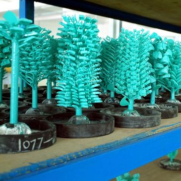 Rows of turquoise plastic sprues on shelves in a manufacturing setting.